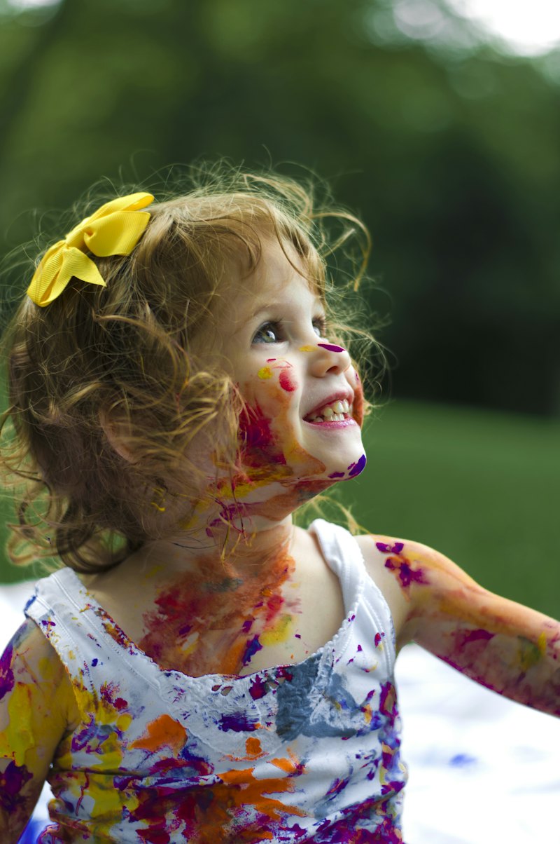 A smiling child with paint on her cheeks, playing outside