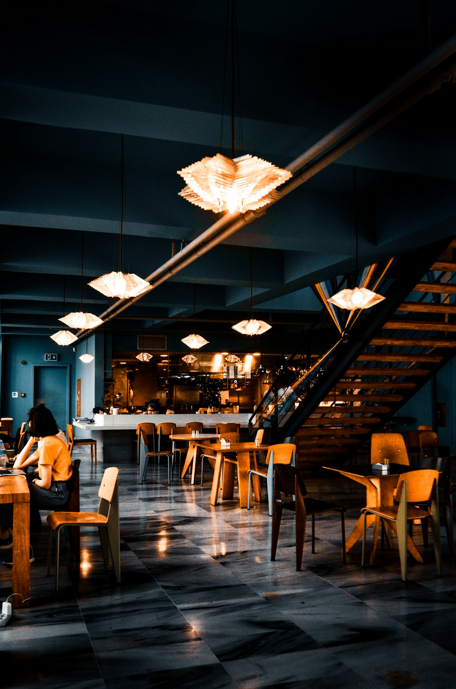 The dining room in the evening, warm lamps over the tables and the staircase